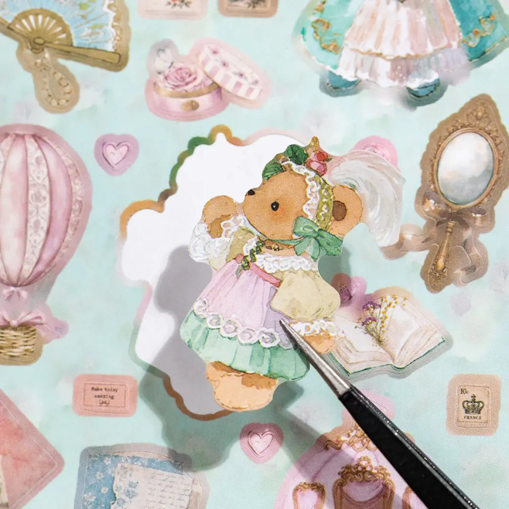 Close-up of a bear sticker being lifted from a Bear Diary sticker sheet with tweezers