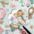 Close-up of a bear sticker being lifted from a Bear Diary sticker sheet with tweezers