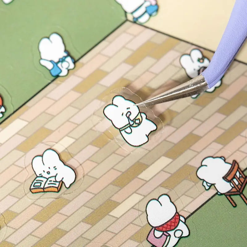 Placing a character sticker onto the Bookshop scene card with tweezers