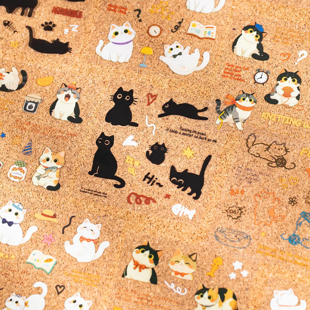Cat Diary Journaling Sticker Set displayed on a cork board with assorted white, black, and kitten sticker designs