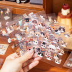 Hand holding transparent PET cat journaling sticker sheets from the Doodle Paper Journal set