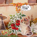 Close-up of an outdoor Cat Journey sticker scene with a cat beside a tomato plant and garden background