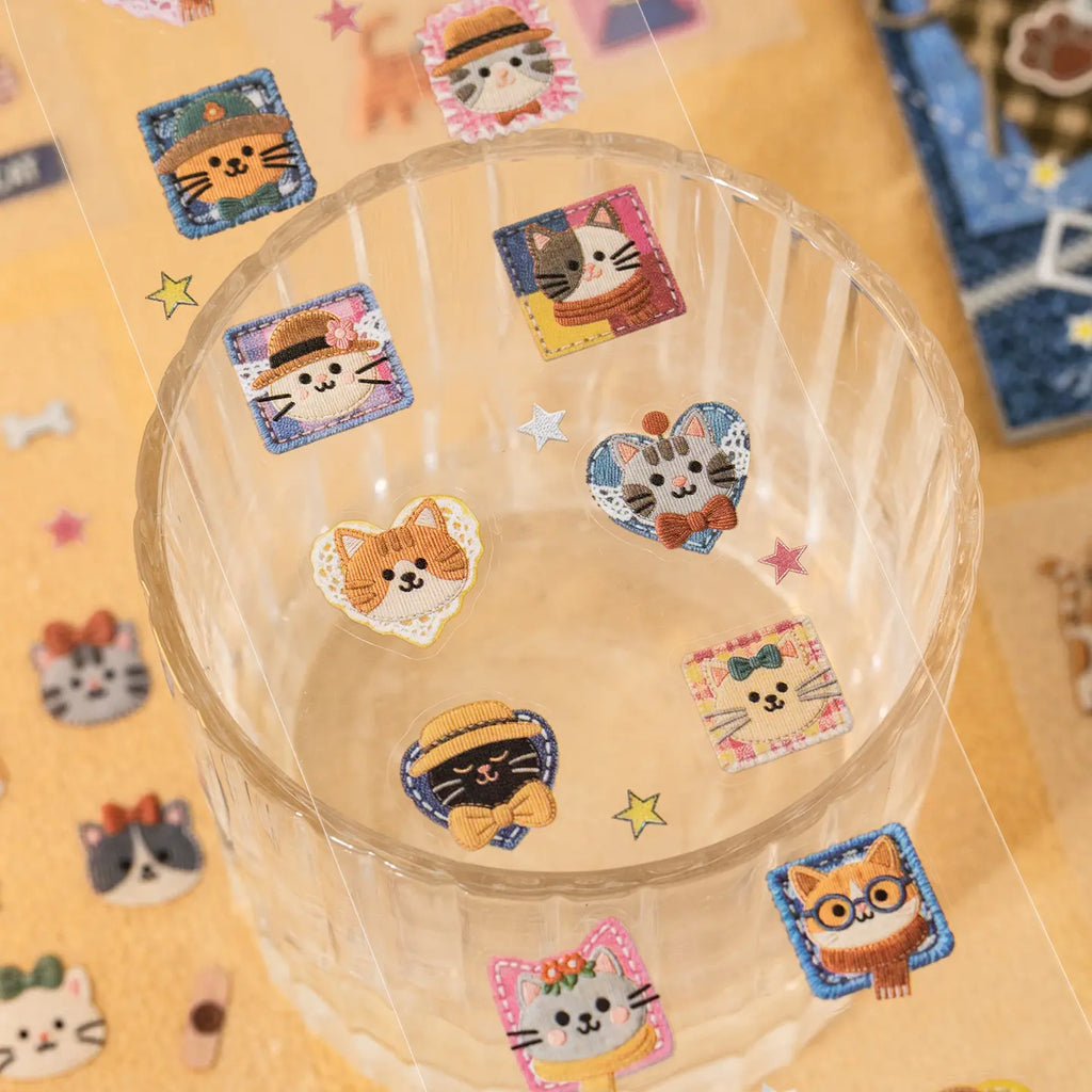 Cat journaling stickers placed on a clear cup with patchwork-style cat faces