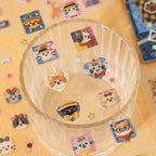 Cat journaling stickers placed on a clear cup with patchwork-style cat faces