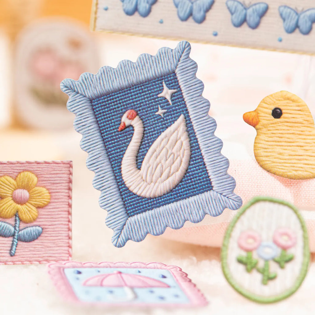 Close-up of a blue framed swan sticker with a printed embroidered stitch effect