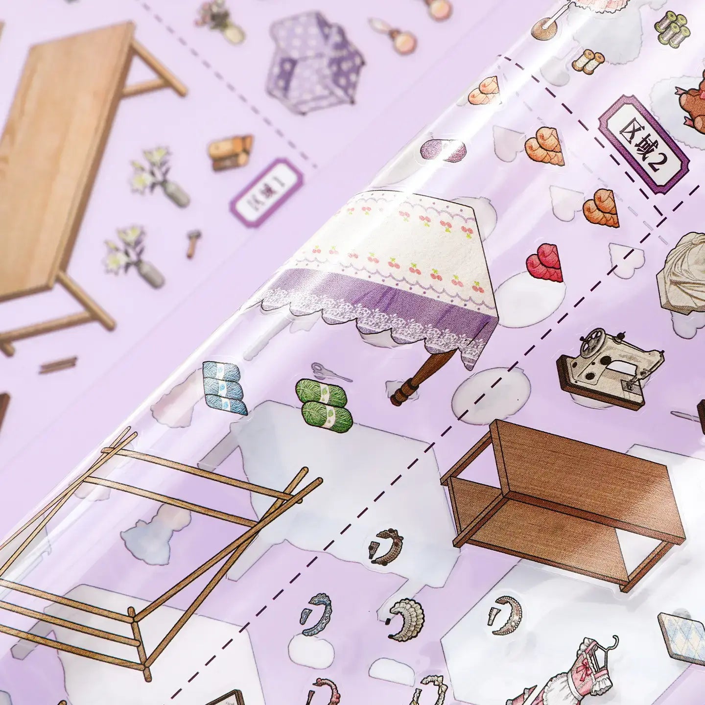 Close-up of glossy PET stickers for the Dreamy Craft Shop scene kit, showing a lampshade, yarn, sewing machine, and craft table pieces