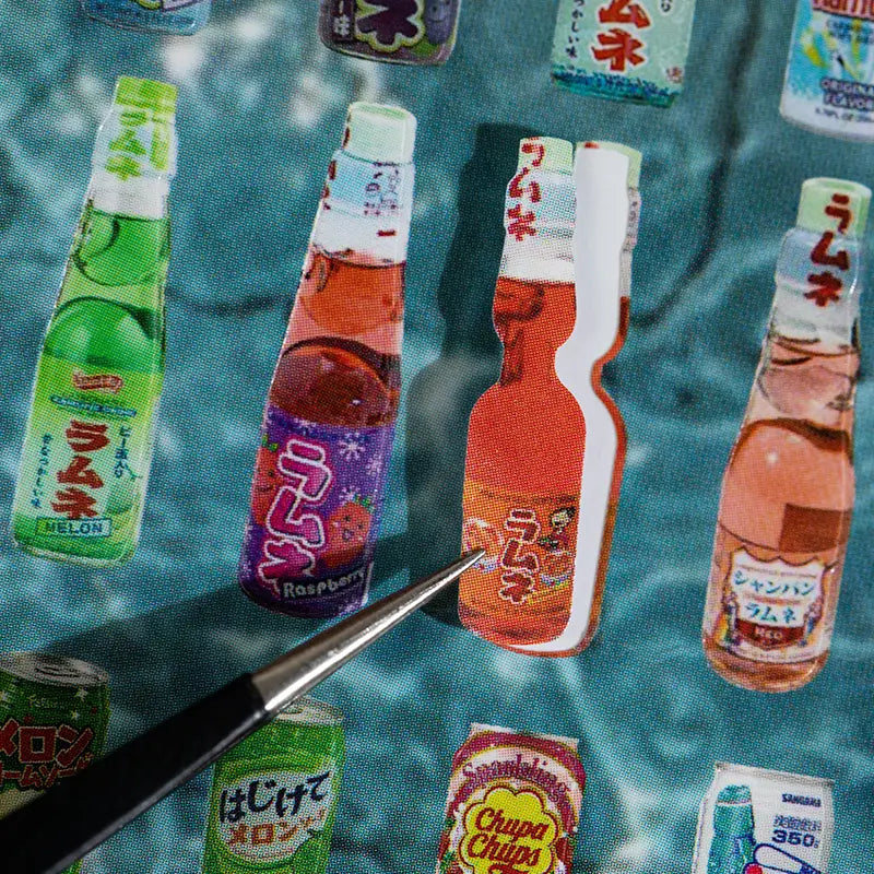 Close-up of a ramune bottle sticker being lifted from the Echoes of Memory Journaling Sticker Book