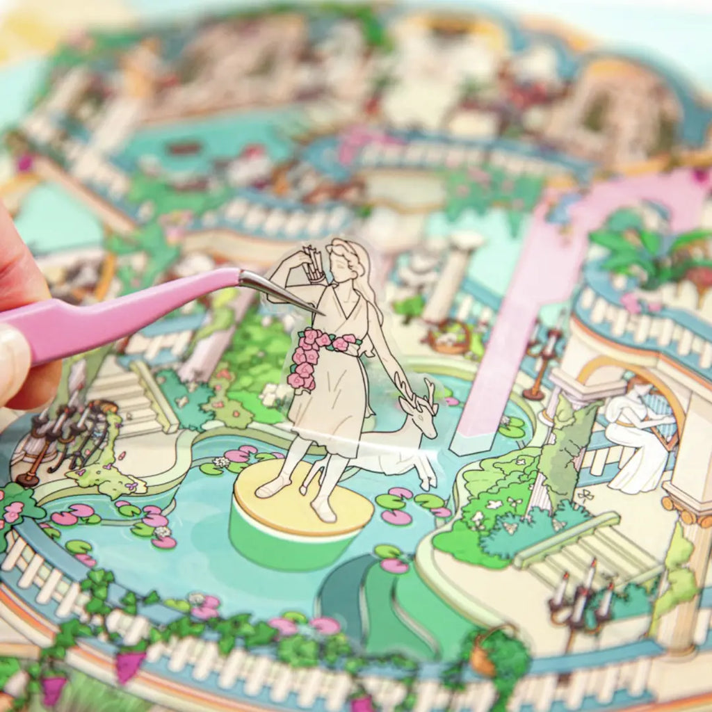 Eden Garden statue sticker being placed onto the garden scene with tweezers