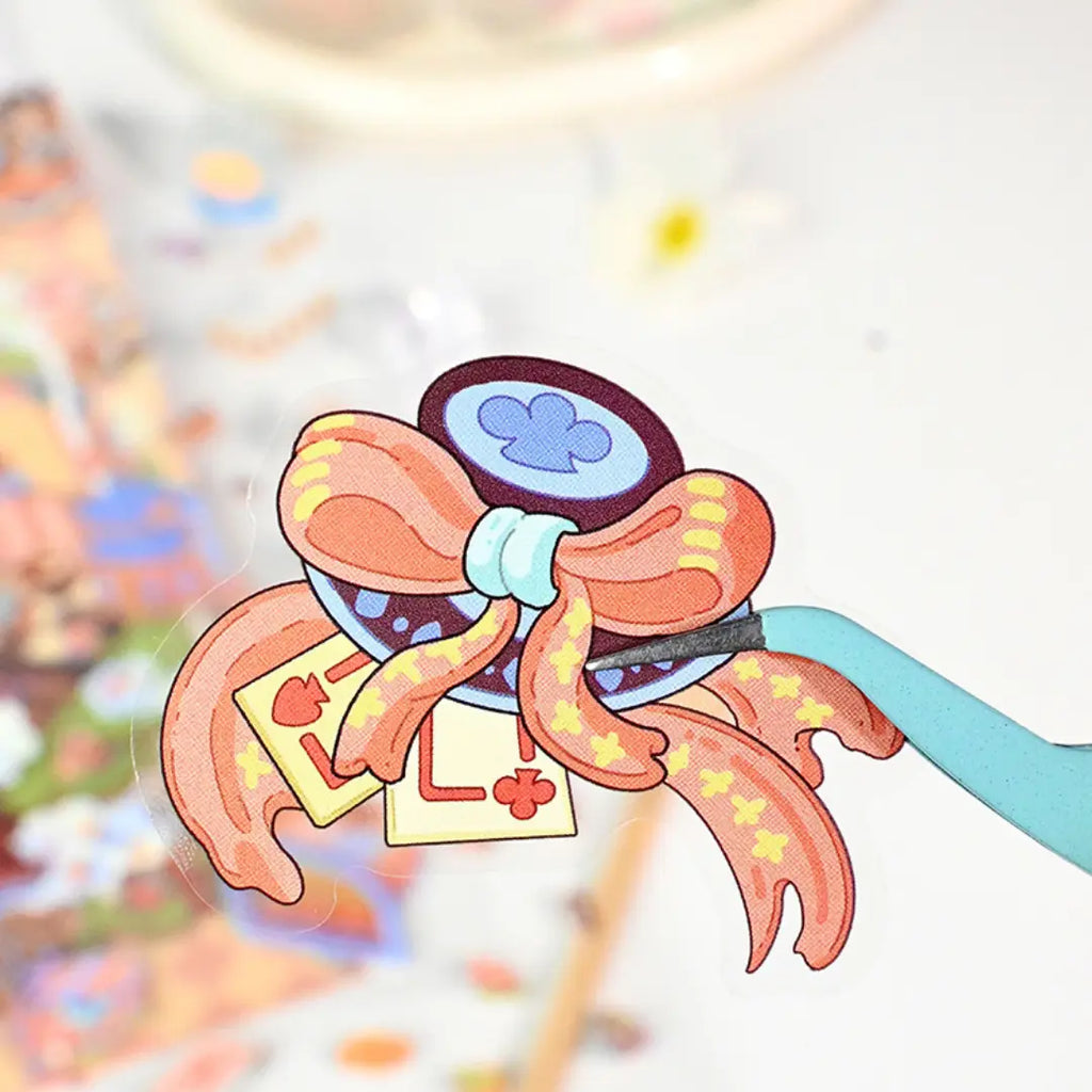 Close-up of a pre-cut bow sticker piece being lifted with tweezers