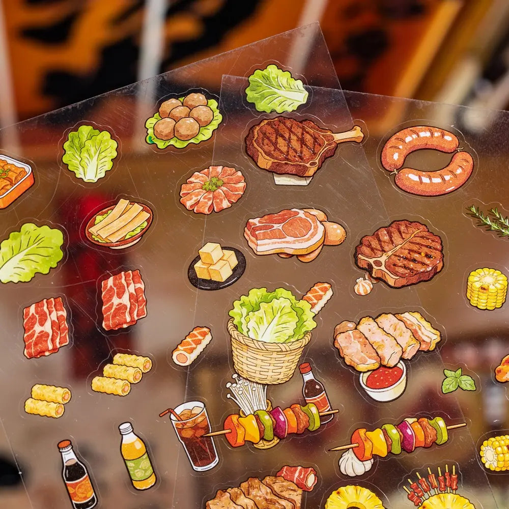 Close-up of miniature food stickers on a transparent sticker sheet with BBQ, meat, vegetables, and drinks
