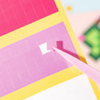 Close-up of a small square sticker block being placed with tweezers