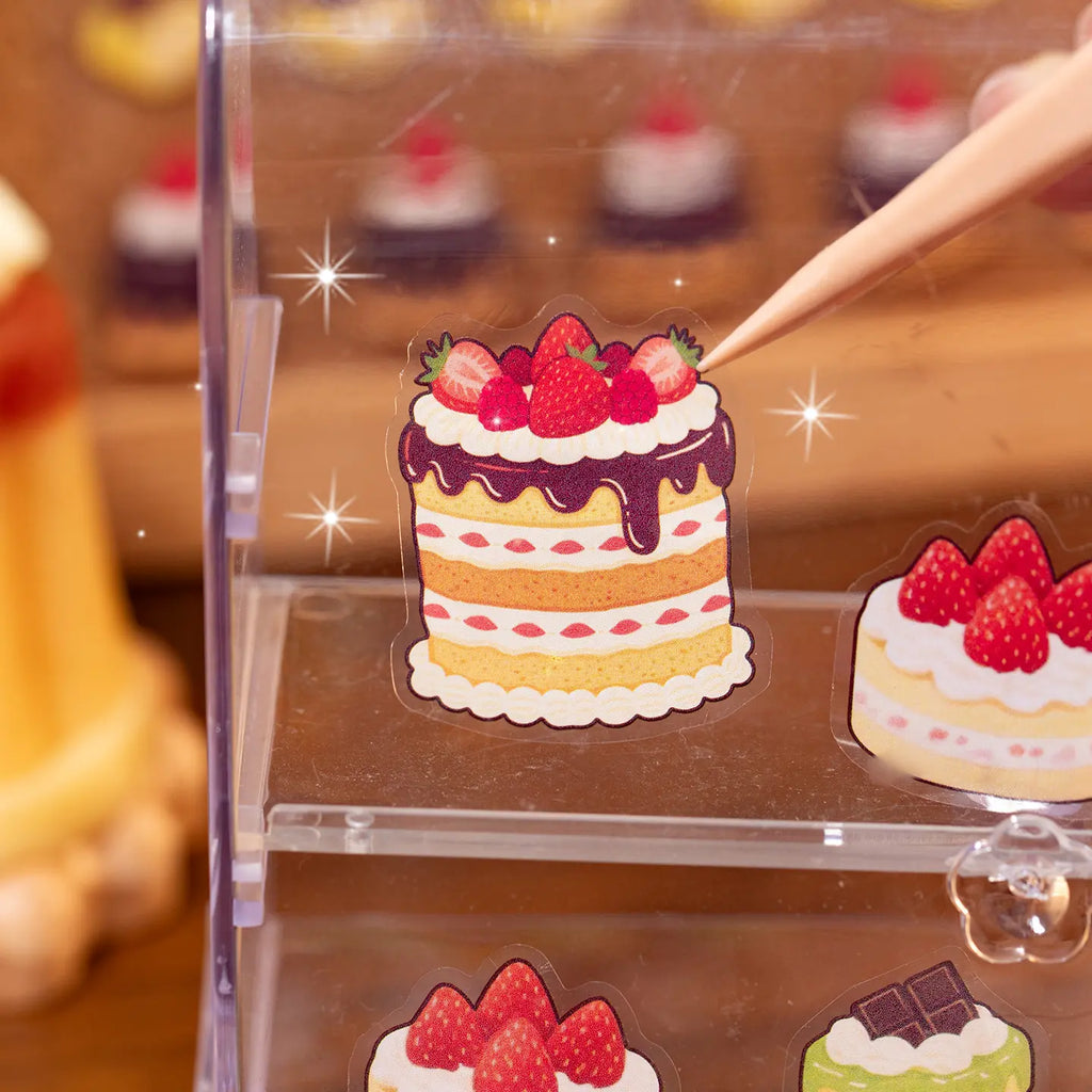 Close-up of a strawberry cake PET sticker placed on a clear display shelf