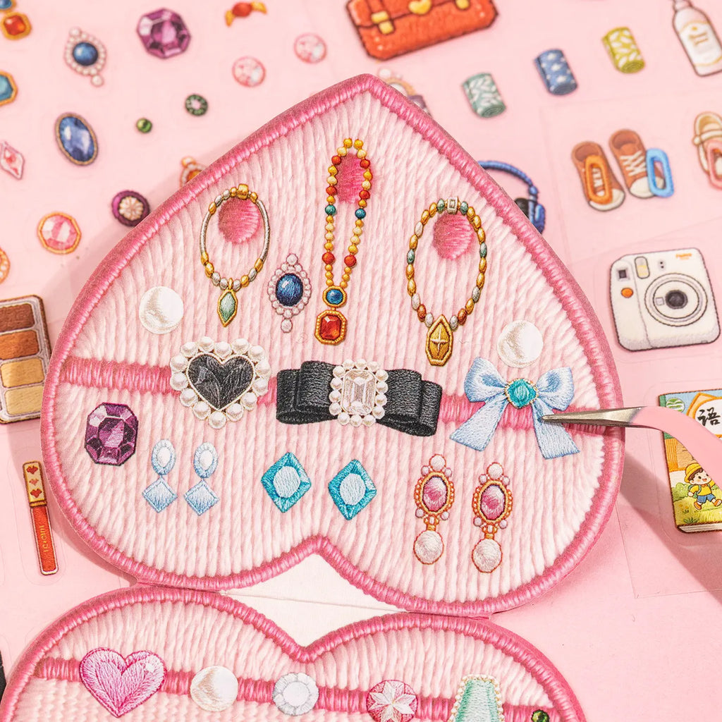 Tweezers arranging flat jewelry stickers inside a pink heart-shaped miniature jewelry box scene