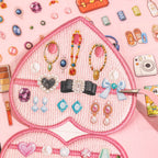 Tweezers arranging flat jewelry stickers inside a pink heart-shaped miniature jewelry box scene