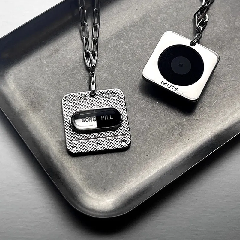 Metallic keychain with 'Song Pill' design on a gray surface