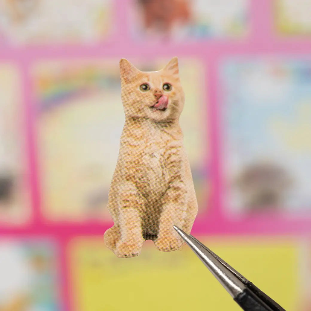 Close-up of an orange cat sticker held with tweezers