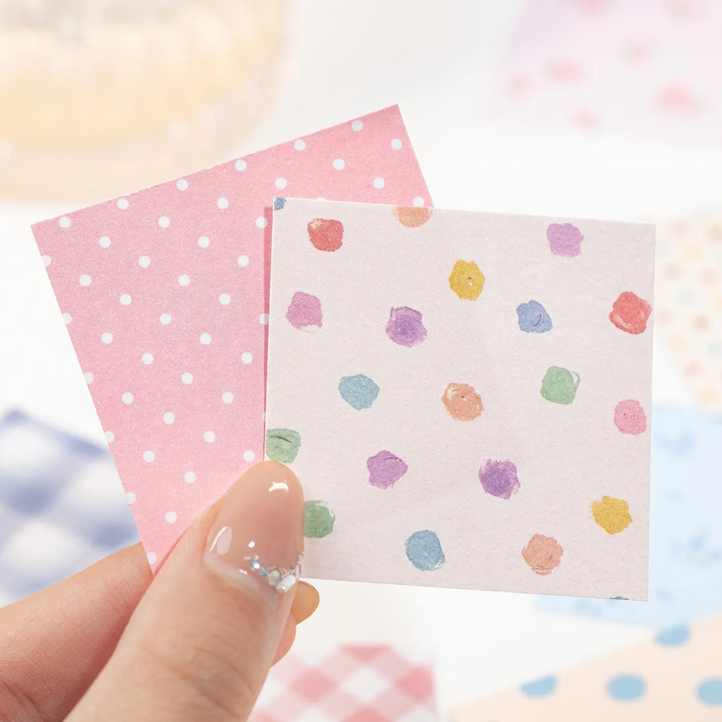 Close-up of two writable square paper stickers with pink dots and multicolored painted spots