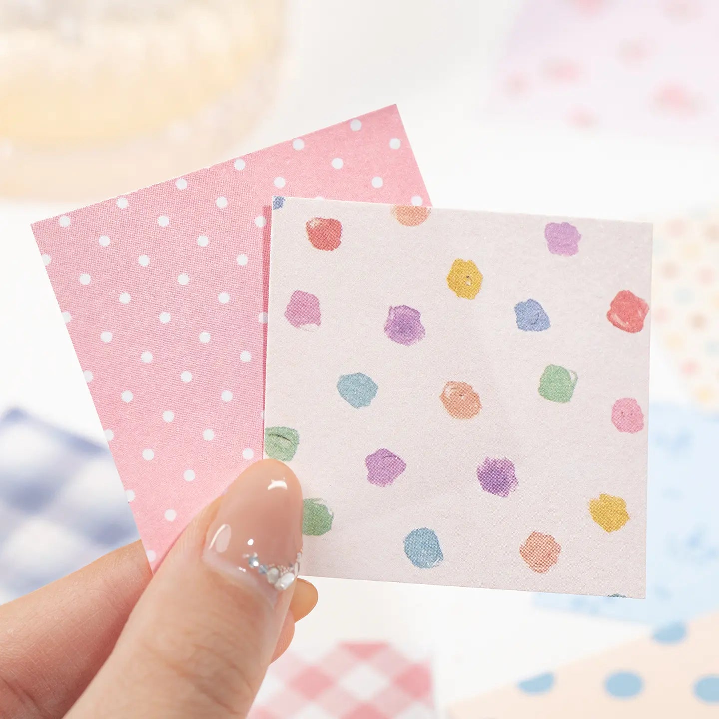 Close-up of two writable square paper stickers with pink dots and multicolored painted spots