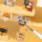 Close-up of a patchwork-style cat sticker on a clear PET sheet