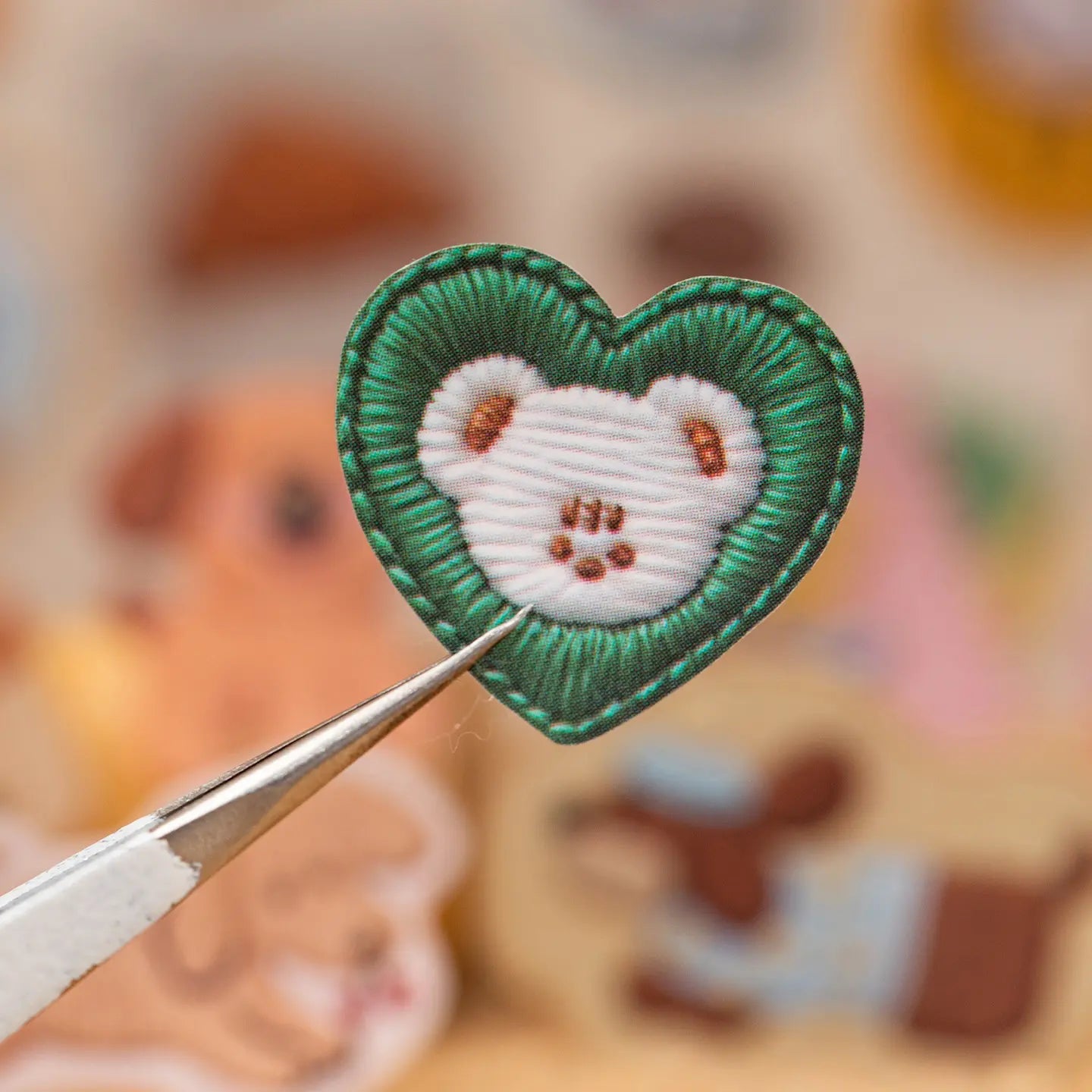 Close-up of a green heart-shaped cat paw sticker with a printed embroidered patch effect