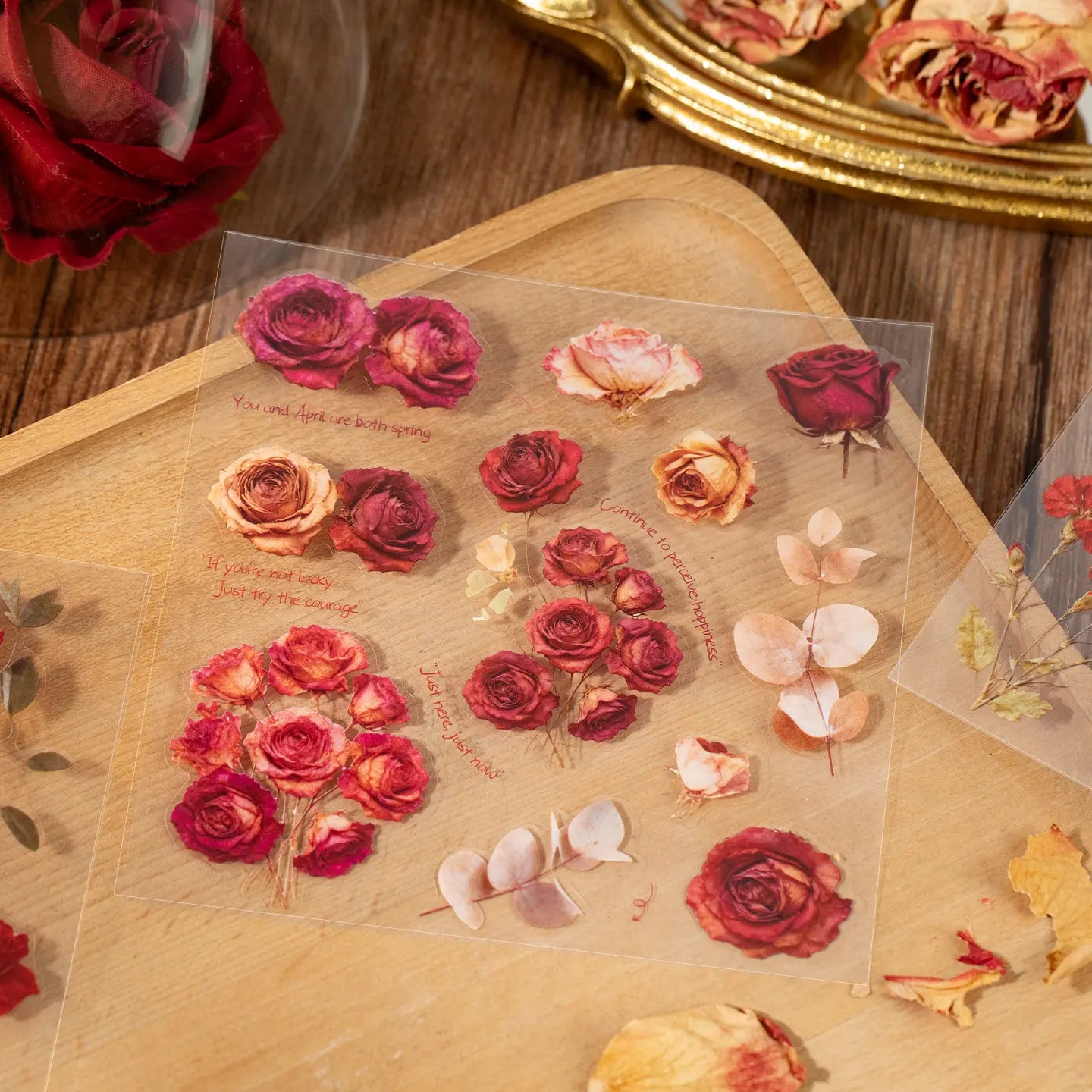 Red rose floral sticker sheet with botanical accents on a wooden tray