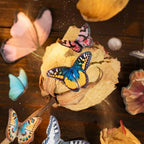 Close-up of butterfly stickers placed around dried flowers in a vintage journaling scene