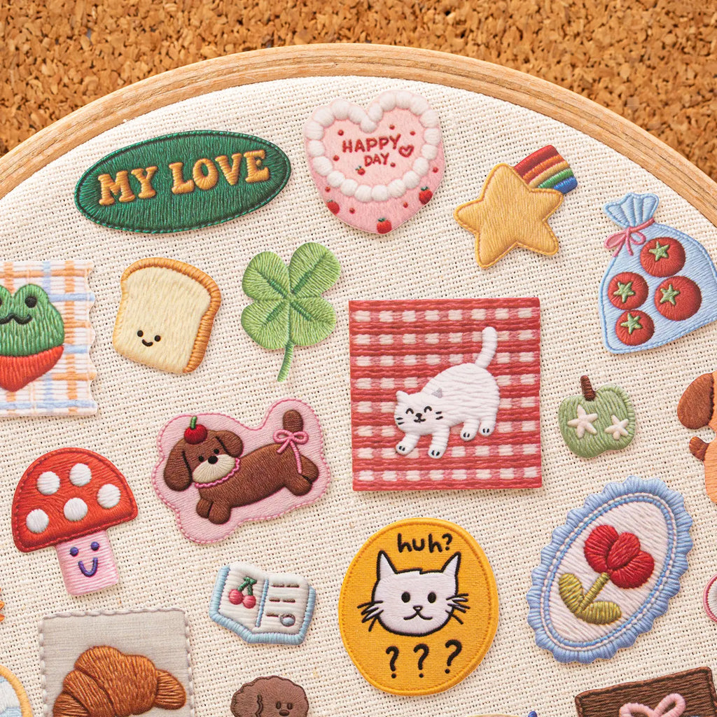 Stitch-look animal, flower, food, and message stickers arranged on a fabric hoop for display