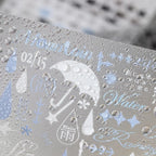 Close-up of a matte transparent Strong Valley sticker sheet with rain and umbrella designs shown with water droplets on the surface