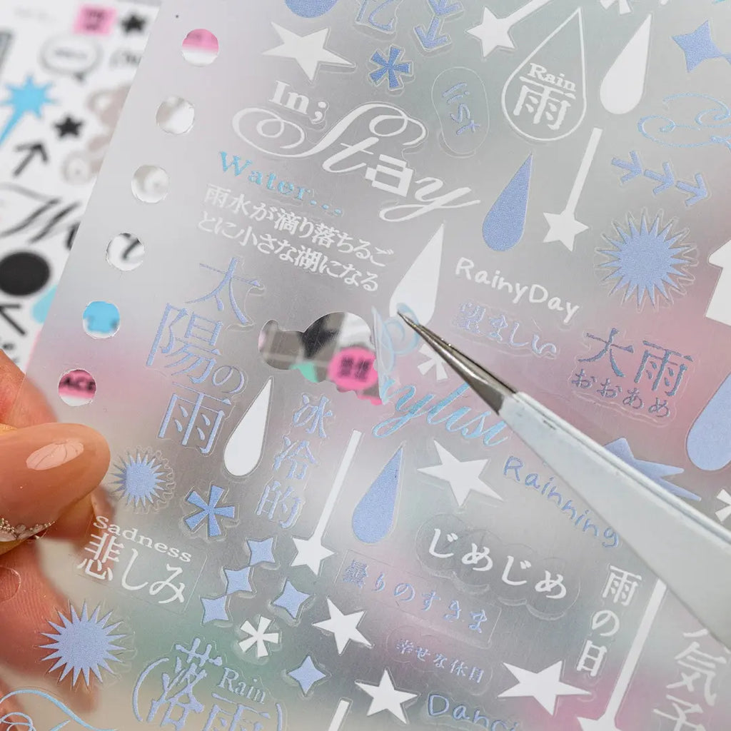 Close-up of a matte transparent weather-themed sticker sheet with rain, stars, arrows, and Japanese-style text accents