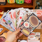 Assorted Tasty Time journaling sticker sheets held in one hand with desserts, fruit, drinks, and food designs