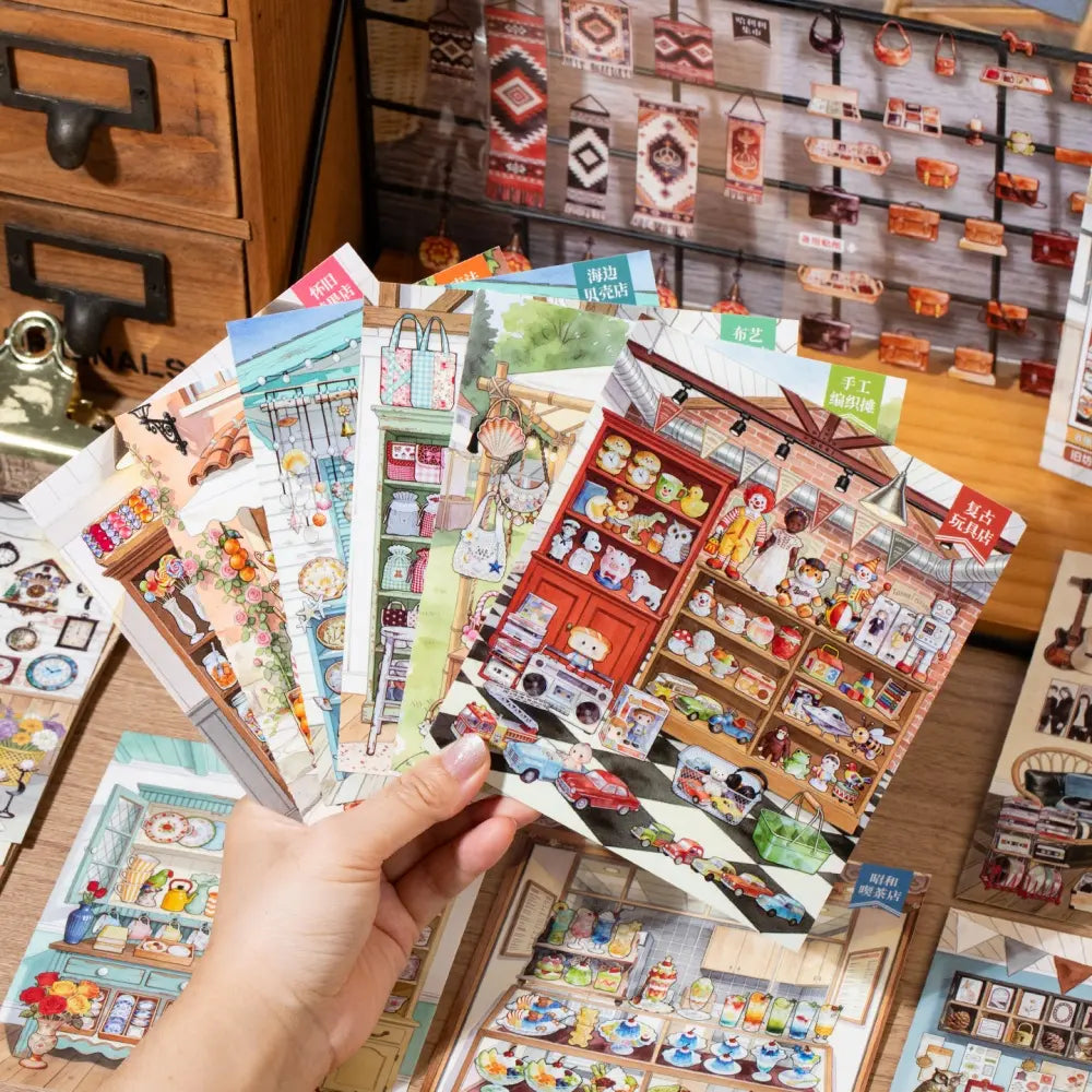 Hand holding multiple scene cards from the Tea Room Therapy Collage Scene Sticker Book