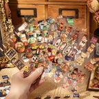 Hand holding transparent PET sticker sheets with bears, flowers, bottles, jewelry, and shop accessories