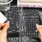 Hands holding clear PET journaling sticker sheets with white stars, borders, music notes, and decorative line designs