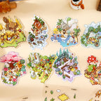 Finished mini scenes from the Woodland Town and Creekside Ferry sticker books arranged on a desk